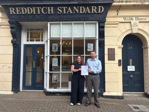 Reps hold signed recognition agreement in front of building 'redditch standard'.