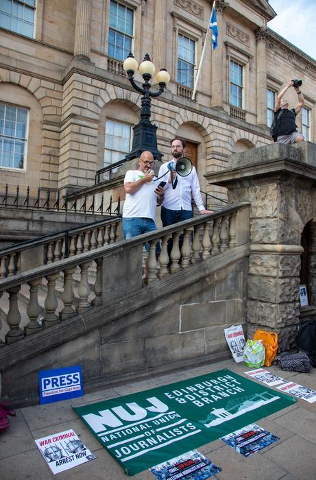 Two people stand on stairs in central Edinburgh with an 'NUJ Edinburgh & District branch' banner laid on the floor in the foreground.