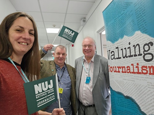 Natasha Hirst, David Nicholson & Nick Powell holding NUJ flags by a Valuing Journalism banner