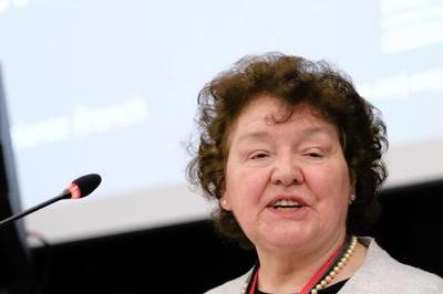 Joyce speaks into mic at the lectern, she has short dark brown hair and a red lanyard. Behind her a screen says motion 67