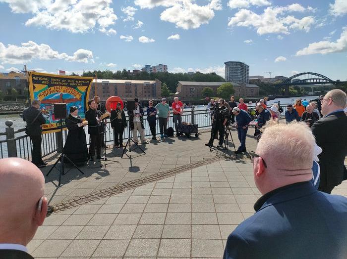 People stand by the river Wear with trade union banners to commemorate the North Sands Massacre.