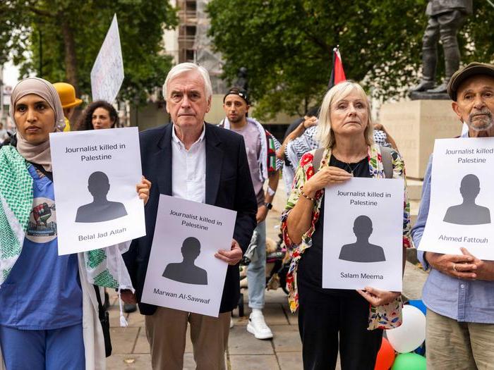 People line the street holding commemorative cards with the names of journalists killed in Gaza.
