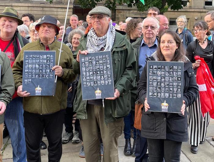 Members at vigil holding posters with names and faces of journalists killed in Gaza