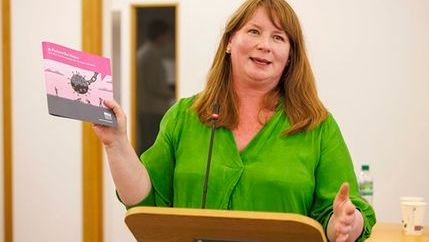 Michelle Stanistret holds up copy of the News Recovery Plan.