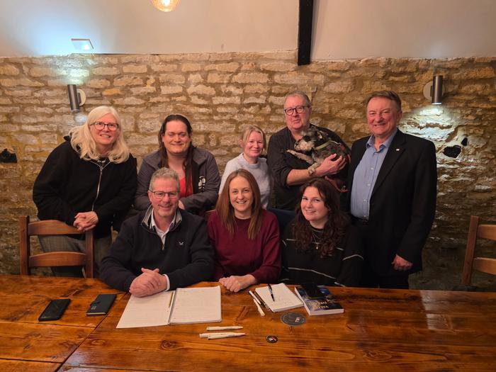 The NUJ Northants branch pose in front of a wooden table.