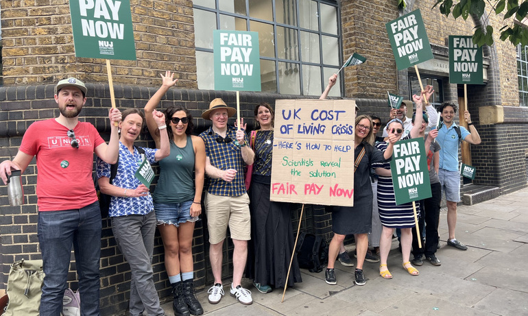 Journalists hold fair pay now placards and wave on the picket line.