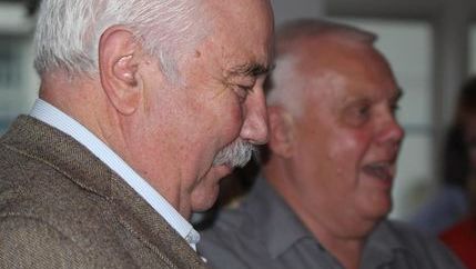 Barry Fitzpatrick, wearing a patterned blazer, looks down while smiling.