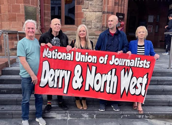The Derry & North West branch hold a red banner on the steps of The Guildhall in Derry.