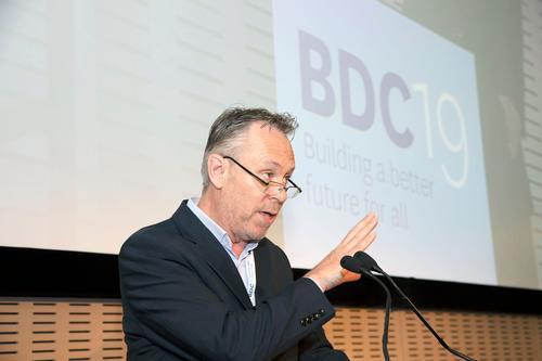 Macdara wears dark suit white white shirt and speaks at lecturn at 2019 ICTU.