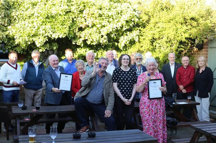 Members of the Sunderland, Shields and Hartlepool branch stand outside with tables in the foreground and trees in the background.