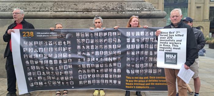 Members holding banner with names and faces of journalists killed in Gaza