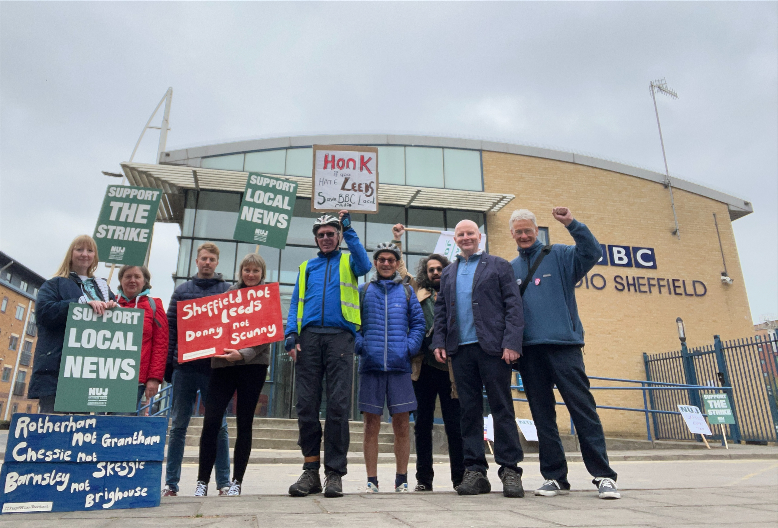 Picket line with placards outside BBC Sheffield with large group smiling