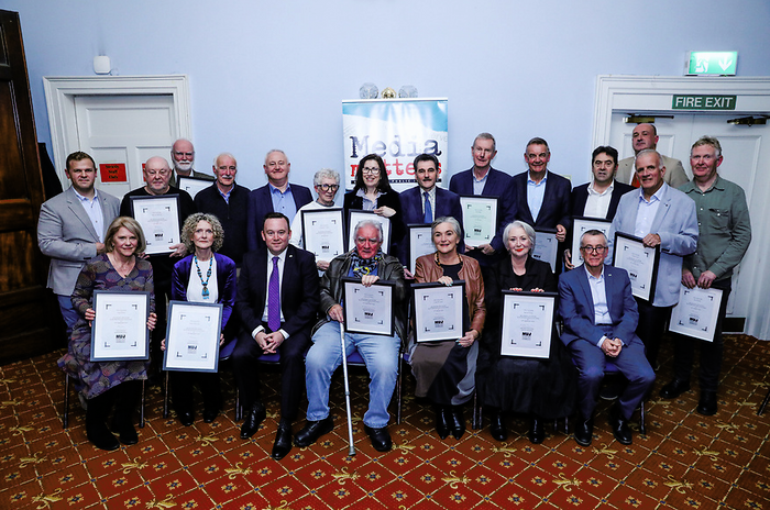 NUJ Life Members pose holding plaques in front of a light blue wall.