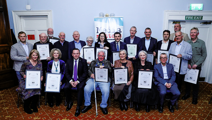 NUJ Life Members pose holding plaques in front of a light blue wall.