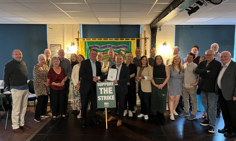 Attendees at Jeff Brown's life membership event pose for a photo. Green placard with white text 'Support the strike' is visible on front row.